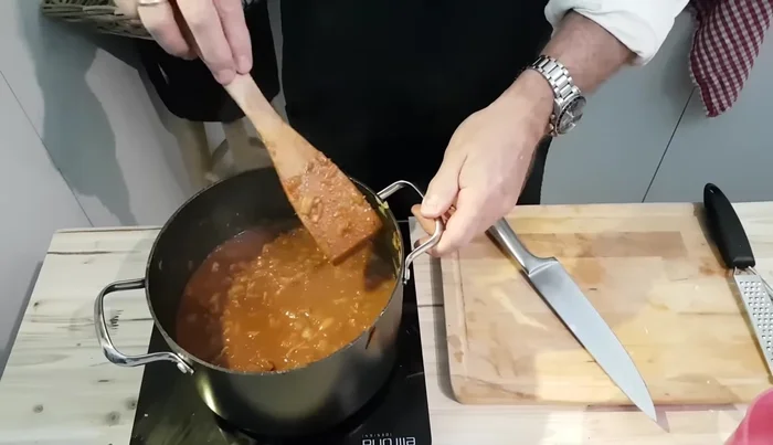 Etwa eine Stunde auf kleiner Flamme köcheln lassen, bei Bedarf etwas Wasser hinzufügen.