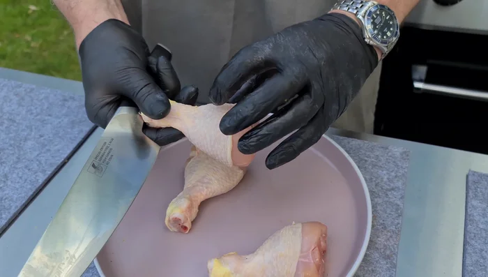 Hähnchenschenkel vorbereiten: Den Muskel vom Knochen lösen, um saftigere Drumsticks zu erhalten. Dafür mit einem scharfen Messer den Muskel vom Knochen trennen (149.63).