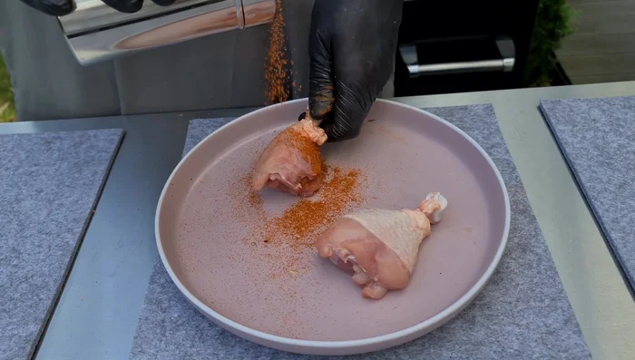 Hähnchenschenkel würzen: Die Haut der Hähnchenschenkel etwas hochziehen, die Gewürzmischung großzügig auf das Fleisch auftragen und die Haut wieder darüberziehen (235.17).