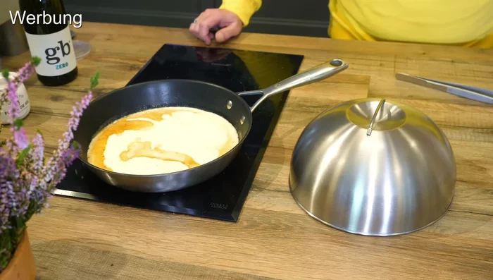 Für die Soße: Sahne und grünen Pfeffer in die Pfanne geben und einköcheln lassen.