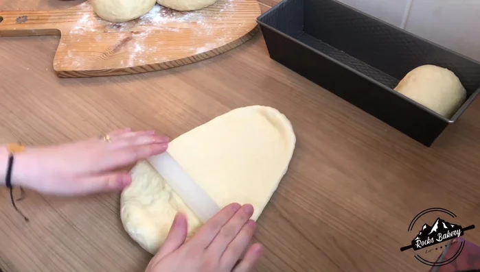 Teiglinge länglich ausrollen, von unten und oben zur Mitte falten, wenden und wieder falten. Festdrücken und in die Form legen.