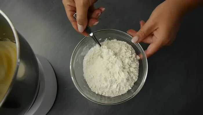 Mehl mit Backpulver vermischen und in zwei Hälften zur Masse geben.