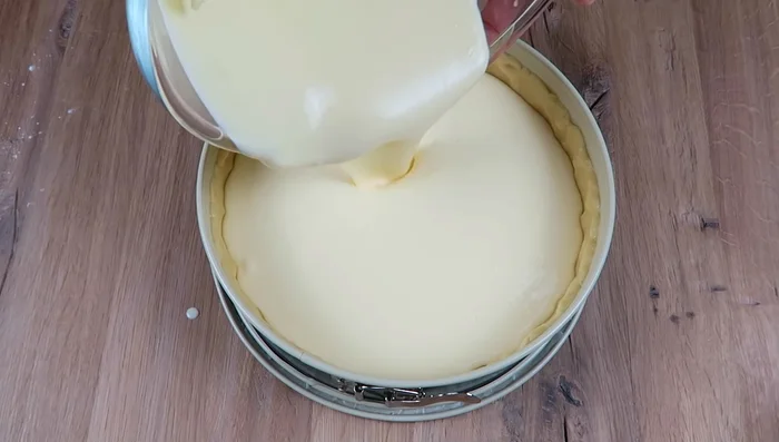 Füllung in die Form geben: Die Füllung in die vorbereitete Form geben. Abgetropfte Mandarinenstücke darauf verteilen.