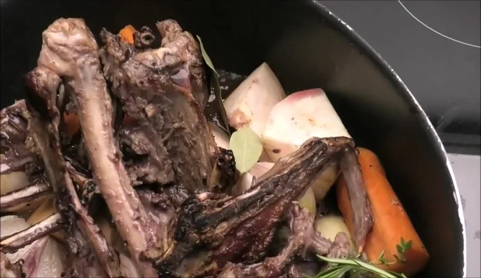 Gewürze (Lorbeer, Wacholder, Salz, Pfefferkörner) zu den Knochen geben.