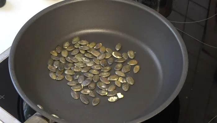 (Optional) Kürbiskerne in einer heißen Pfanne ohne Öl rösten, bis sie goldbraun sind.