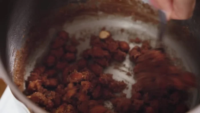 Die Masse unter ständigem Rühren köcheln lassen, bis das Wasser verdampft ist und der Zucker karamellisiert.