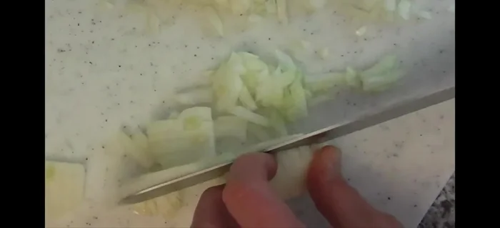 Zwiebeln fein würfeln und auf die Schnitzel verteilen (63.199).