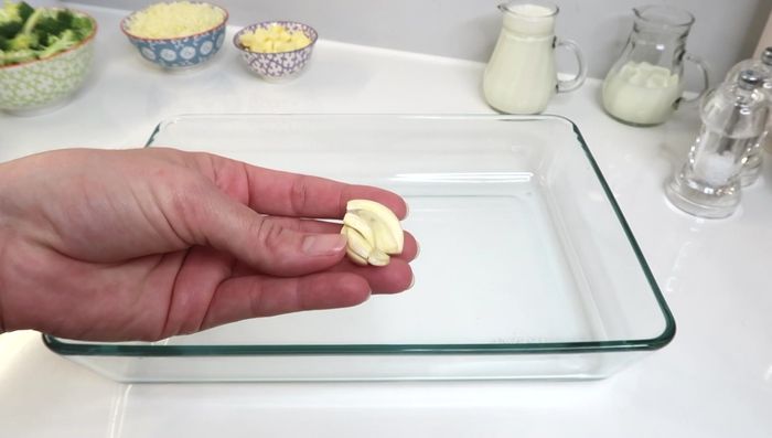 Auflaufform mit Knoblauchzehe ausreiben und mit Butter einfetten.