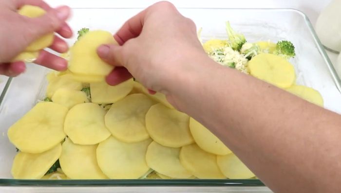 Eine zweite Schicht Kartoffeln, Salz, Pfeffer, Butterflocken, Brokkoli und Käse hinzufügen.