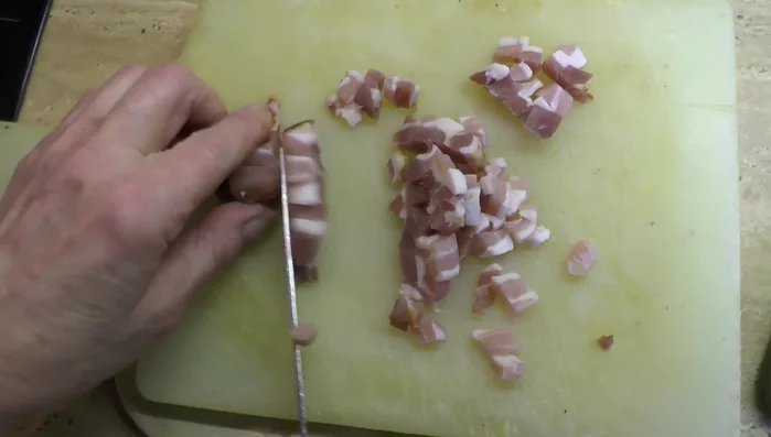 Speck in kleine Stücke schneiden.