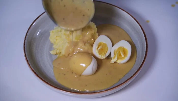 Eier mit Senfsoße servieren, mit Petersilie garnieren.