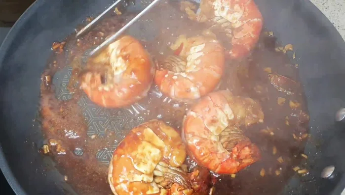 Garnelen nach kurzer Zeit wenden und weiterbraten, bis sie rosa sind und die Flüssigkeit zu einer geleeartigen Konsistenz eingedickt ist.