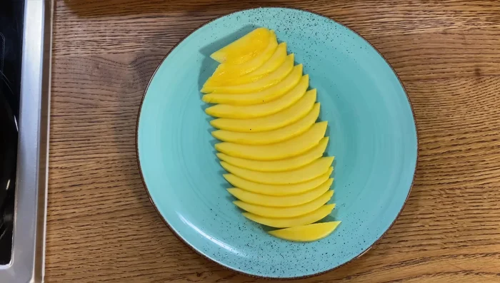 Mangoscheiben auf einem Teller verteilen, mit Salz, Pfeffer, Avocado Topping, Limettensaft und optional Mango-Chili-Öl oder Sesamöl beträufeln.