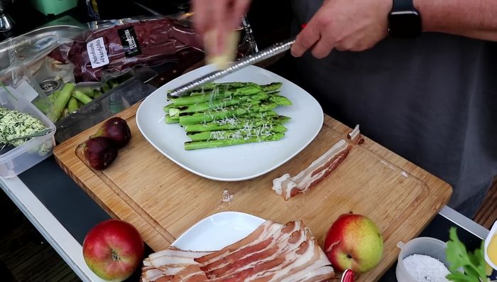 Spargel mit Parmesan bestreuen und mit Speck umwickeln. Auf der Feuerplatte grillen.