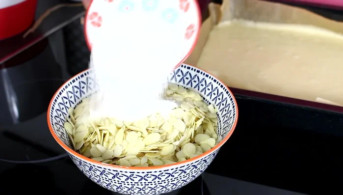 Zucker mit Mandelblättchen vermischen und auf den Teig streuen.