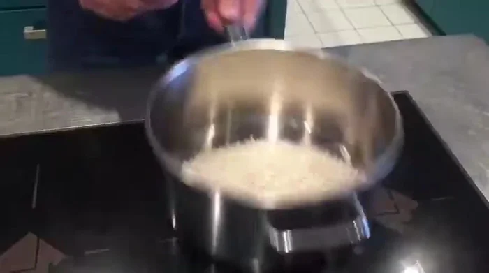 Reis rösten: Den Reis in einem Topf ohne Öl unter ständigem Rühren so lange erhitzen, bis die gesamte Feuchtigkeit verdunstet ist und der Reis eine leicht goldene Farbe annimmt. (114.96)