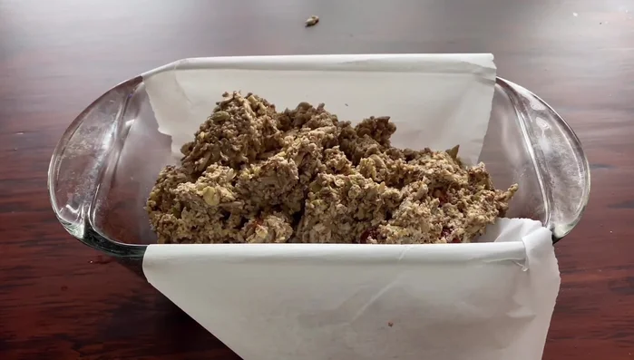 Den Teig gleichmäßig in die vorbereitete Kastenform füllen und gut andrücken, um Luftlöcher zu vermeiden.