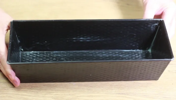 Kastenform einfetten und Teig einfüllen. Gleichmäßig verteilen.