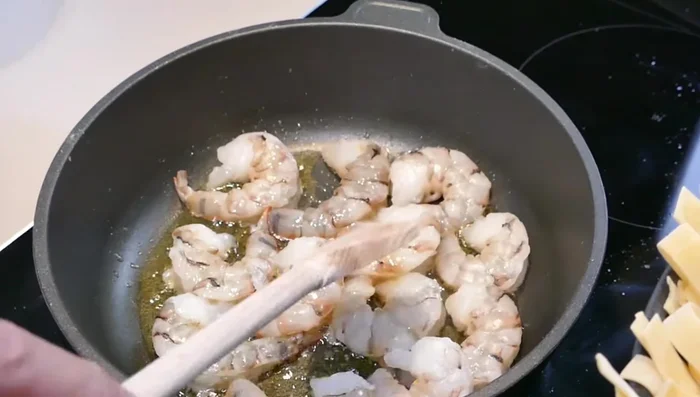 Garnelen in einer Pfanne mit Olivenöl von beiden Seiten scharf anbraten, bis sie fest geworden sind (109.49). Nicht zu lange braten, sonst werden sie gummiartig (120.08).