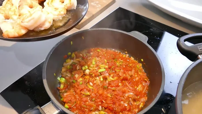 Die angebratenen Garnelen in die Tomatensauce geben und erwärmen (256.28).