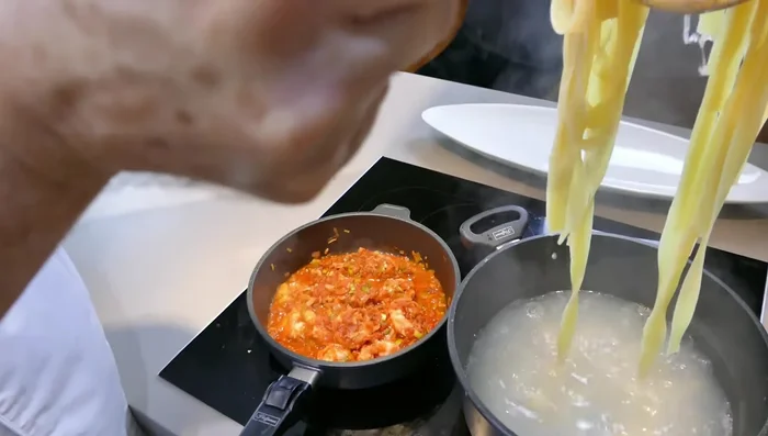 Die gekochten Bandnudeln abgießen und unter die Sauce heben (286.07).