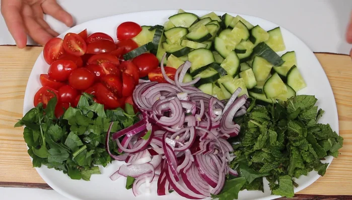 Tomaten und Gurken in Stücke schneiden. Zwiebel und Petersilie vorbereiten.