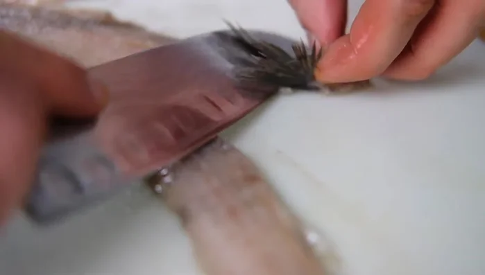 Matjes in Würfel schneiden und zu den Zwiebeln und Gurken geben.