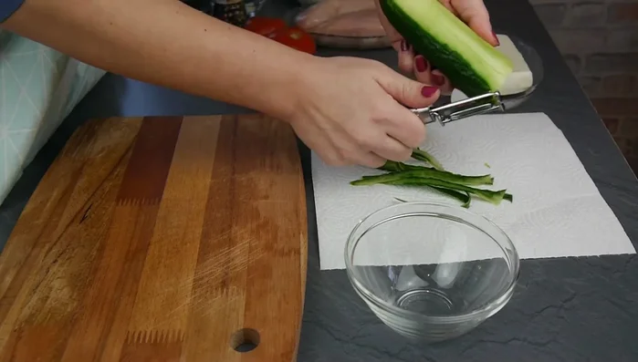 Eisbergsalat in feine Streifen schneiden. Gurke schälen und in kleine Stücke schneiden. Tomate entstrunken und in feine Stücke schneiden.
