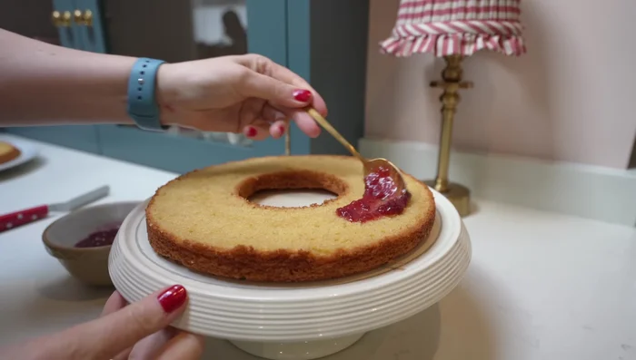 Erste Kuchenschicht mit Himbeermarmelade bestreichen.