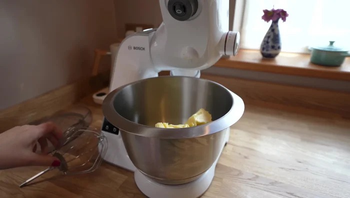 Buttercreme auf die erste Schicht geben, weitere Schichten hinzufügen und mit Himbeermarmelade bestreichen.