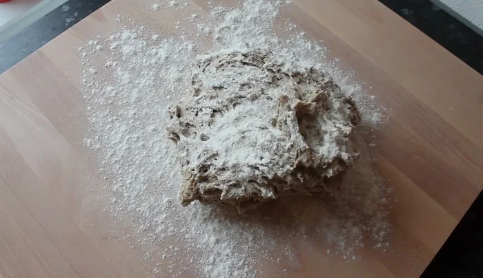 Teig von außen nach innen ziehen und durchkneten, bis er eine leichte Mehlschicht hat.