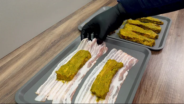 Bacon leicht überlappend auf einem Backblech auslegen. Marinierte Bauchscheiben darauflegen, Seiten einschlagen, oberen Teil umklappen und auf den unteren Baconteil drehen, um die Form zu erhalten.