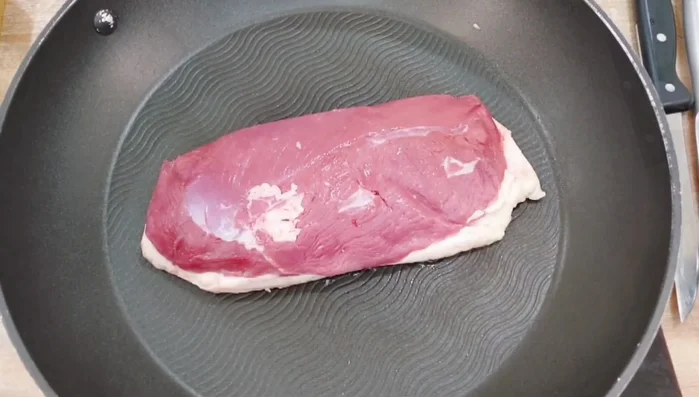 Entenbrust mit der Hautseite nach unten in eine kalte Pfanne legen und ohne Fettzugabe bei höchster Stufe 5-6 Minuten anbraten.