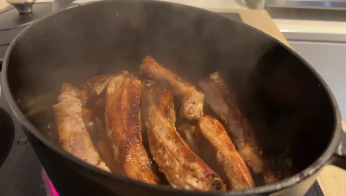 Rippchen zum Gemüse geben, gut vermischen und etwas reduzieren lassen. Nochmal etwas Rotwein hinzufügen.